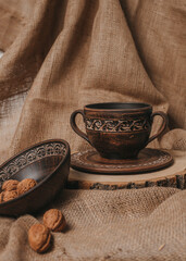 Handmade ceramic craft ware. Rustic napkin and kitchen tools. Plate on a wooden stand with nuts. Handmade ceramic dishes