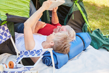 Fototapeta na wymiar Senioren Paar liegt entspannt vor einem Zelt
