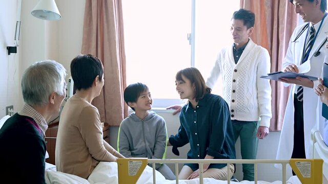 家族が入院中のおばあさんを訪れて、会話を楽しんでいる。