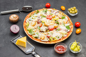 Pizza with ingredients is ready to bake. Vegetables and meat, cheese grater, pizza cutter