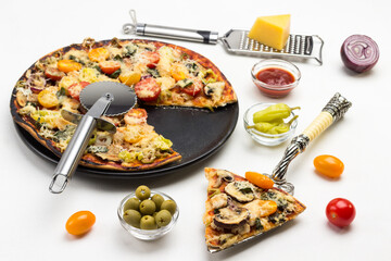 Slice of pizza on scoop. Ready pizza on black plate. Pizza cutter on pizza. Grater with cheese. Olives and tomatoes