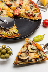 Slice of pizza on scoop. Ready pizza on black plate. Pizza cutter on pizza.