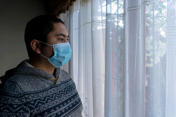 Man looking out window with mask