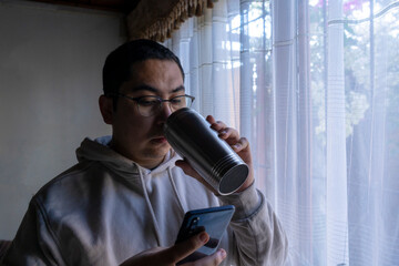 Man with checking his mobile phone and drinking coffee from a thermos