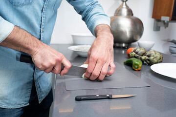Cropped view of male cutting vegetables on chopping board at kitchen