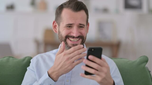 Young Man Celebrating on Smartphone at Home 