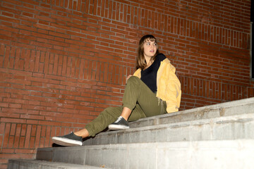 Young blond girl sitting on staircase outdoors in the city at night - Powered by Adobe