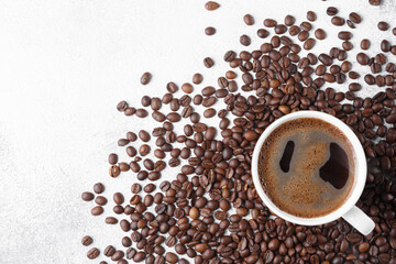 Cup of coffee with coffee beans on gray stone background. Top view