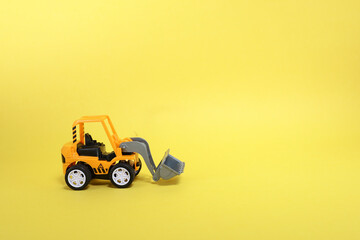 A yellow toy bulldozer isolated on yellow background 