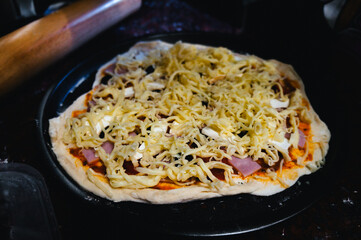Homemade pizza cheese in a black tray on the table.