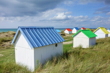 Fototapeta na wymiar Beach huts in the dunes. Picturesque colorful wooden beach cabins at Gouville-sur-Mer, Cotentin, Normandy, France