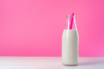 Glass bottle of milk against pink background