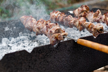 Mouth- watering skewers of pork with a toasted Golden crust and smoke flavor. Barbecue with coals in the yard in nature with cooked meat on skewers