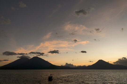 Guatemala, Central America: sunset with boats at lake Atitlán (Atitlan) with volcanos Atitlan, Toliman, SanPedro