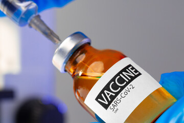 Covid-19 vaccine bottle with a syringe taking the vaccine from it