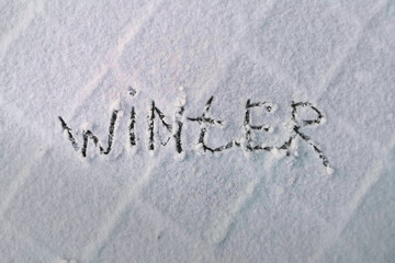 Inscription winter on snow-covered sidewalk tile - Winter Christmas Background