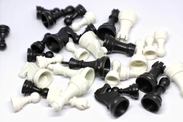 Plastic small black and white chess pieces scattered on white isolated background