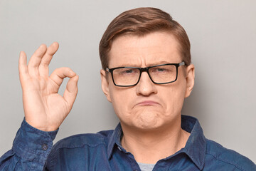Portrait of proud confident blond mature man showing okay gesture