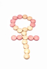 Pink and orange pills and capsules making a female sex or gender sign on white background -symbolizing medicalization or sex change surgery or transgender women