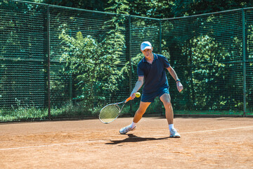 Active senior Caucasian man in sportswear playing tennis, hits a forehand groundstroke