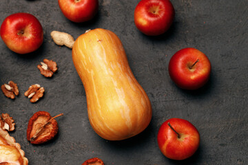 One pumpkin and red apples on black surface top view