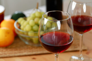 Two wine glasses with red wine on wooden kitchen counter