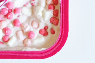 White milk yogurt with sweet balls and marshmallows in a red plastic box. Baby sweetness. Free space for an inscription