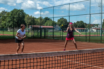 Two active senior Caucasian women in sportswear playing tennis