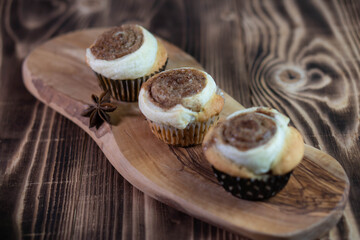 Cinnamon cupcakes on a wooden board and textured brown wooden table