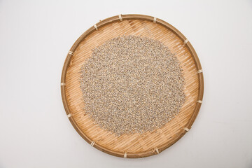 Unhulled unpolished barley in bamboo dish on white background