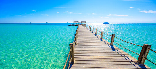 Wooden Pier at Orange Bay Beach with crystal clear azure water and white beach - paradise coastline of Giftun island, Mahmya, Hurghada, Red Sea, Egypt. - 392267443