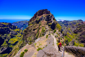 Beautiful hiking trail from Pico do Arieiro to Pico Ruivo, Madeira island. Footpath PR1 - Vereda do Areeiro. On summy summer day above the clouds. Portugal. - obrazy, fototapety, plakaty