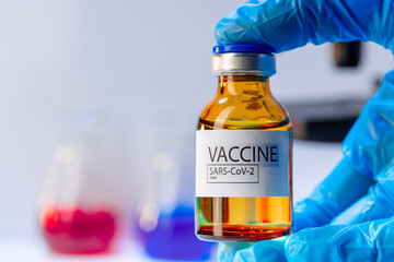 Doctor hands in blue gloves holding Sars-cov-2 vaccine vial