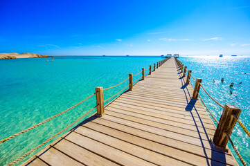 Wooden Pier at Orange Bay Beach with crystal clear azure water and white beach - paradise coastline of Giftun island, Mahmya, Hurghada, Red Sea, Egypt.