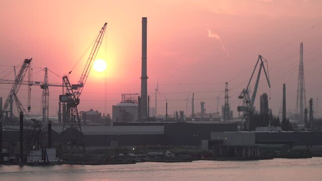 Industrial landscape of factories and wind power generators at sunset.