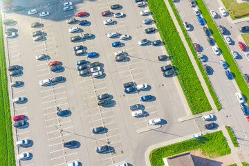 Aerial top down view of the parking lot with many cars of supermarket shoppers in the city grocery store.