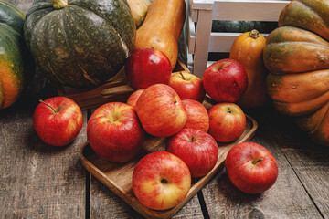 Pumpkins and red apples on wooden background