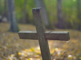 Old Wooden Crucifix on Forgotten Grave in Cemetery Deep in the Woods