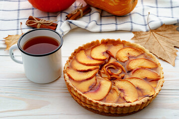 Apple tart pie on table with pumpkin and dry leaves