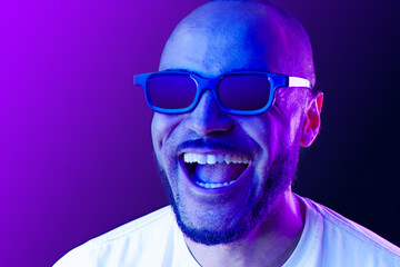 Positive black man in glasses posing in neon lights