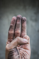 A young man showing his hands holding three fingers on a gray background.