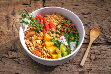 Green smoothies, cereals and fresh fruit in a bowl on a wooden table