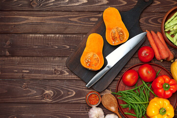 Small pumpkin cut into halves on wooden cutting board with knife