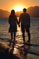 Fototapeta premium Silhouettes of girls and boys holding hands against the background of the sunrise in the sea. Sunrise in Icmeler.