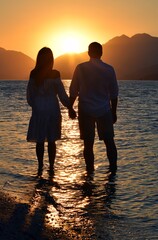 Silhouettes of girls and boys holding hands against the background of the sunrise in the sea. Sunrise in Icmeler.