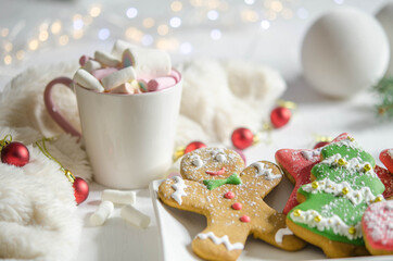 Gingerbread cookies and marshmallows in a cup on a blurred background.