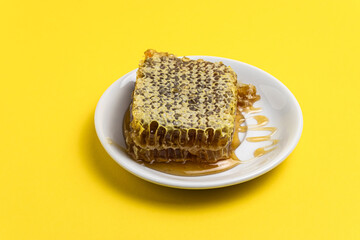 Honey in combs in a plate on a yellow background