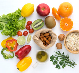 Top view apples,parsley,orange,kiwi,tomatoes,lemon colourful fruits and nuts set on white wooden background in concept healthy food the best way to get fit, diet food and detox.Vegetarian breakfast.