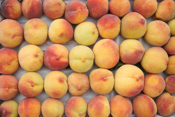 Naklejka na ściany i meble Freshly harvested peach background. Ripe peach stacked