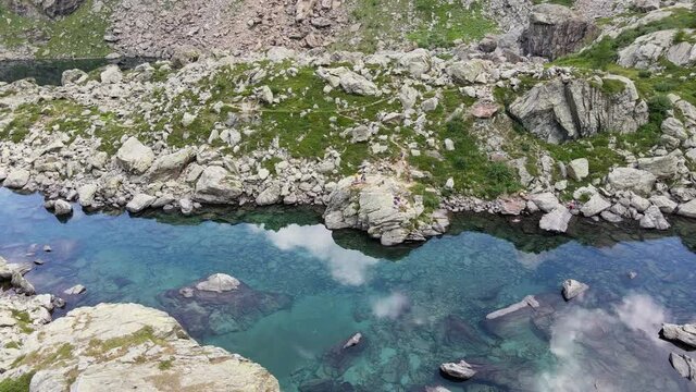 Aerial view of small mountain lake with water reflaction in the Alps. Drone flight footage 4K UHD